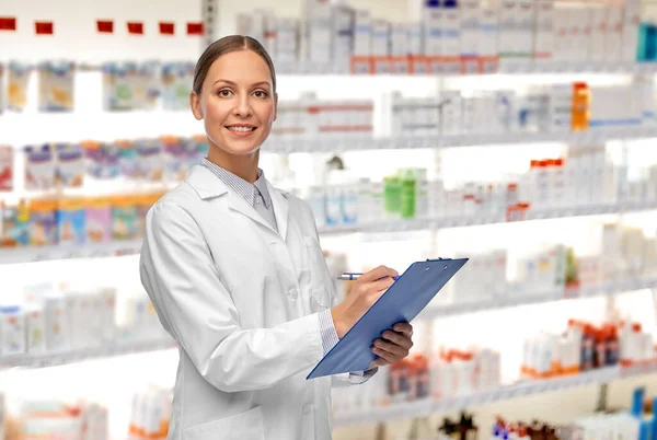 Glimlachende vrouwelijke arts met klembord bij de apotheek — Stockfoto