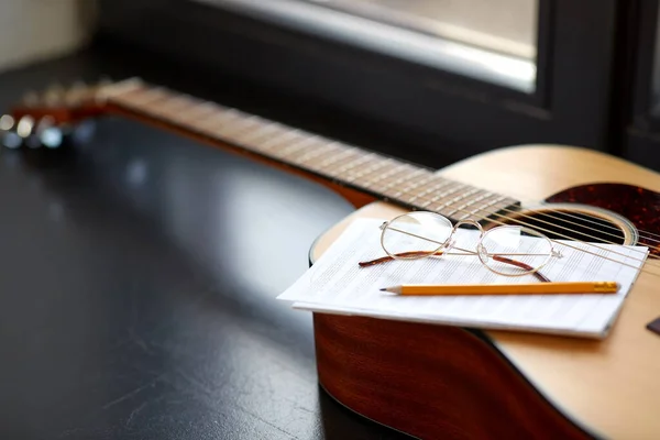 Close-up van gitaar, muziekboek, potlood en bril — Stockfoto