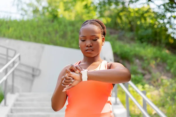 Mujer africana con reloj inteligente haciendo deportes —  Fotos de Stock