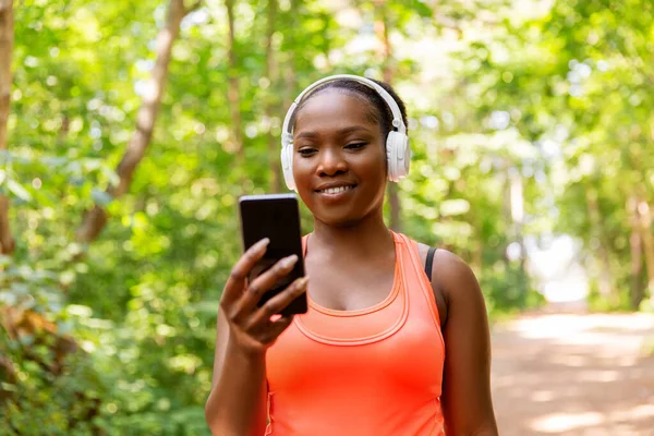 Kulaklığı ve telefonu olan Afrikalı Amerikalı bir kadın. — Stok fotoğraf