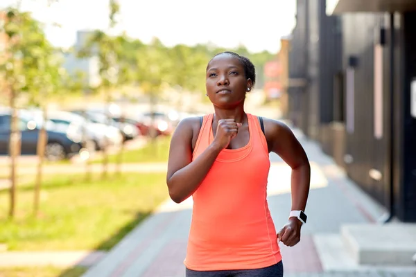 Africká žena s chytrými hodinkami běží ve městě — Stock fotografie