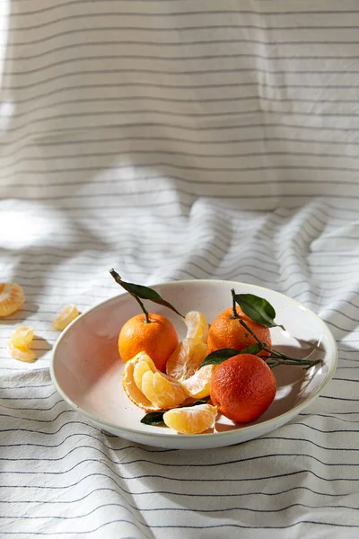 Still life with mandarins on plate over drapery — Stock Photo, Image