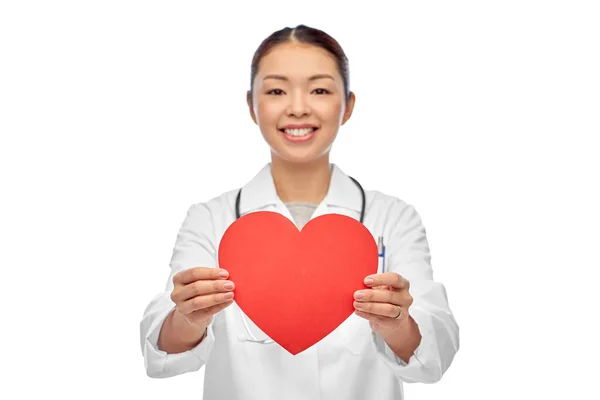 Sonriente asiático mujer médico holding rojo corazón —  Fotos de Stock