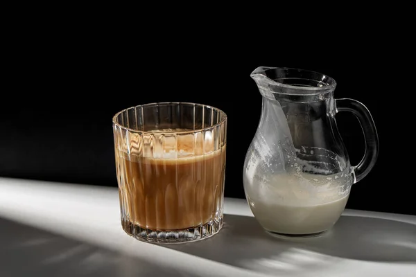 Καφέ σε ποτήρι και κανάτα γάλακτος ή κρέμας γάλακτος στο τραπέζι — Φωτογραφία Αρχείου
