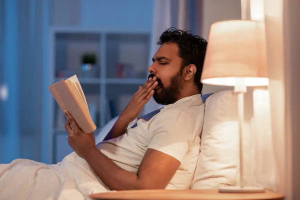 夜にベッドで本を読んでいるインド人男性を — ストック写真