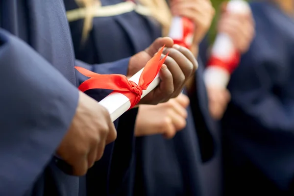 Estudiantes graduados en tableros de mortero con diplomas Imagen de stock