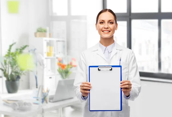 Lächelnde Ärztin mit Klemmbrett im Krankenhaus — Stockfoto