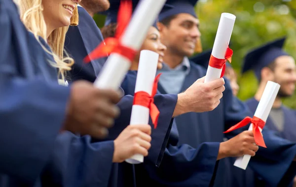 Estudiantes graduados en tableros de mortero con diplomas — Foto de Stock