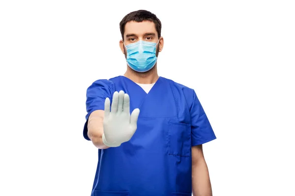 Doctor masculino en uniforme azul y máscara mostrando stop — Foto de Stock