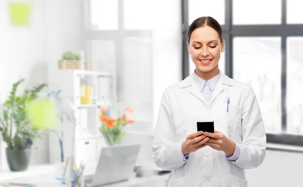 Gelukkige vrouwelijke arts met smartphone in het ziekenhuis — Stockfoto