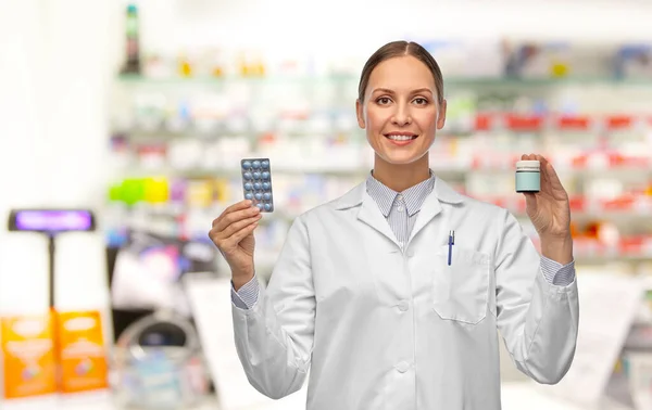 Medico sorridente femminile che tiene la medicina in farmacia — Foto Stock