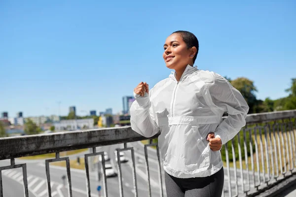 Mujer afroamericana corriendo a lo largo del puente — Foto de Stock