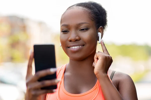 Africká americká žena se sluchátky a telefonem — Stock fotografie