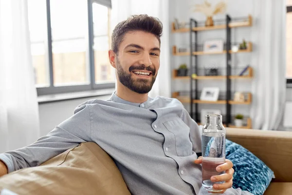 Hombre feliz beber agua de botella de vidrio en casa —  Fotos de Stock