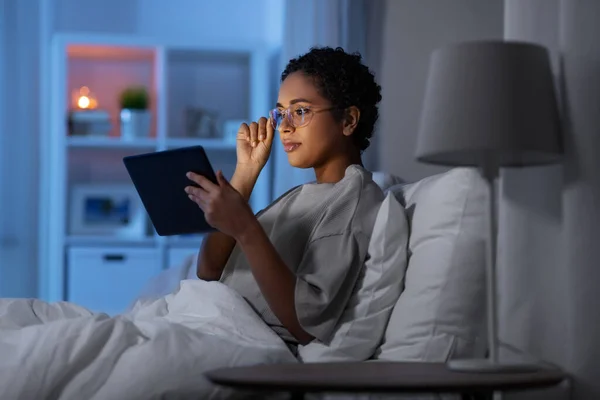 Wanita dengan tablet pc di tempat tidur di rumah di malam hari — Stok Foto