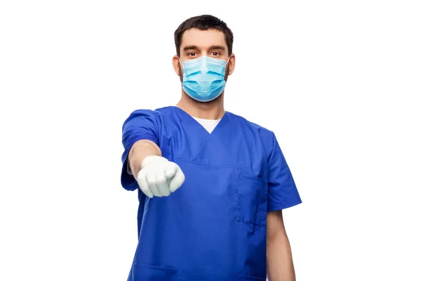 Male doctor in blue scrubs and mask points finger — Stock Photo, Image