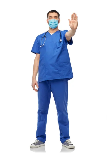 Arzt in blauer Uniform und Maske zeigt Anschlag — Stockfoto