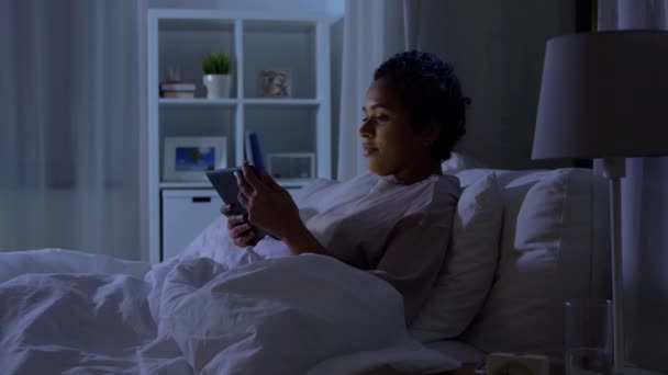 Žena s tabletou PC v posteli doma v noci — Stock video