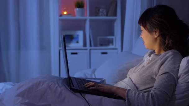 Žena s notebookem pracuje v posteli v noci — Stock video