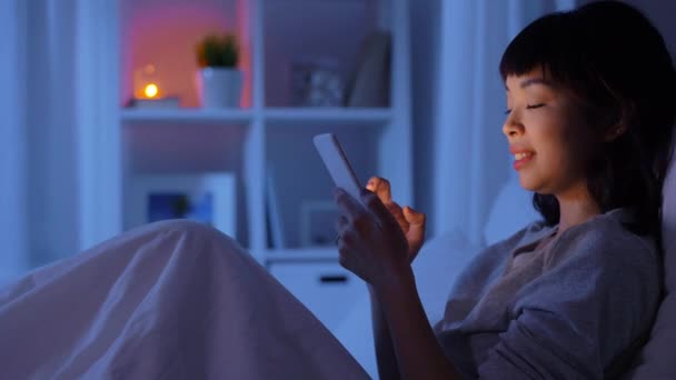 Žena s chytrým telefonem v posteli doma v noci — Stock video