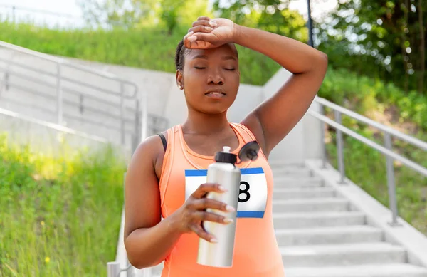 Vermoeide vrouwelijke marathonloper met fles water — Stockfoto