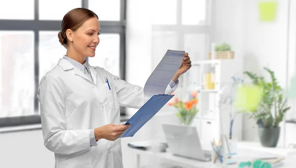 Happy female doctor with clipboard at hospital — Stock Photo, Image