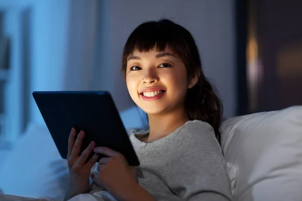 Mujer asiática con tableta pc en la cama en casa por la noche — Foto de Stock