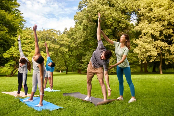 Grupo de personas haciendo yoga con instructor en el parque —  Fotos de Stock