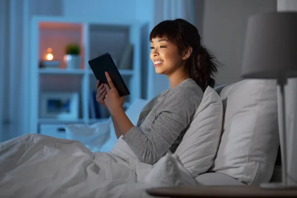 Ázsiai nő tabletta pc az ágyban otthon éjszaka — Stock Fotó