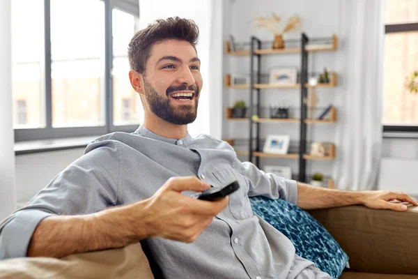 Homem feliz com controle remoto assistindo tv em casa — Fotografia de Stock