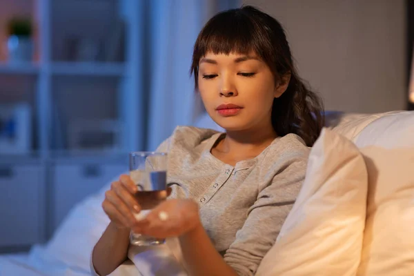 Stressad asiatisk kvinna som tar medicin på natten — Stockfoto