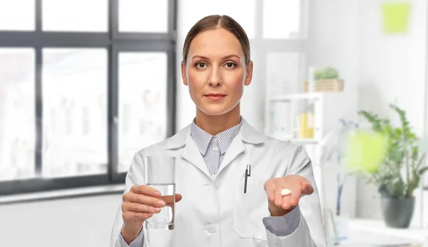 Kvinnlig läkare med medicin och glas vatten — Stockfoto