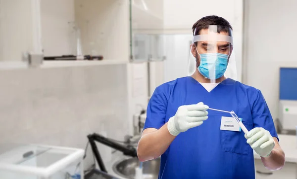 Médico masculino con máscara con hisopo de algodón y tubo de ensayo —  Fotos de Stock