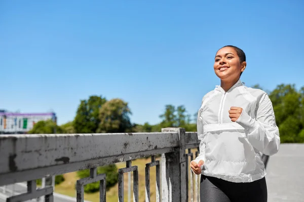 Mujer afroamericana corriendo a lo largo del puente — Foto de Stock