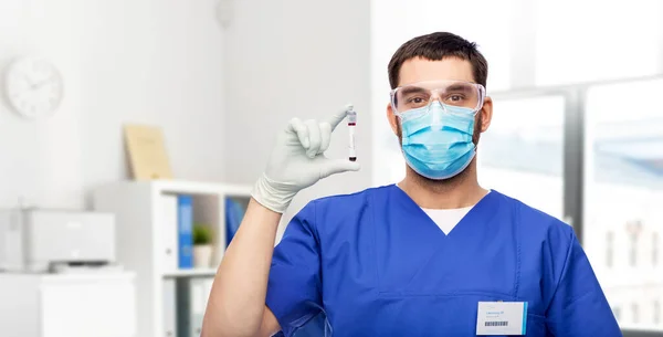 Médico varón con mascarilla y sangre en tubo de ensayo — Foto de Stock