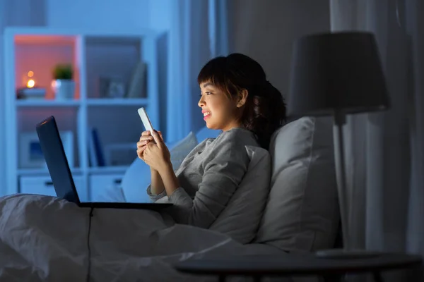 Wanita asia dengan smartphone di tempat tidur di malam hari — Stok Foto