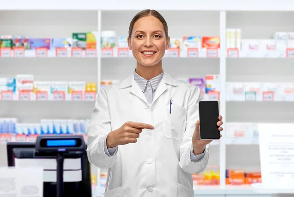 Szczęśliwy lekarz kobieta ze smartfonem w aptece — Zdjęcie stockowe