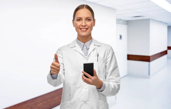 Femme médecin avec smartphone montrant pouces vers le haut — Photo