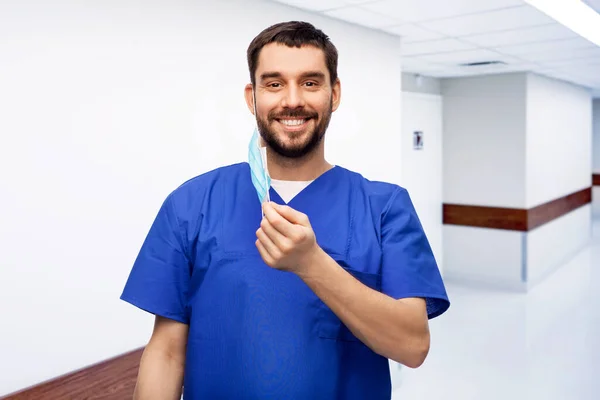 Sorridente medico di sesso maschile in uniforme blu con maschera — Foto Stock