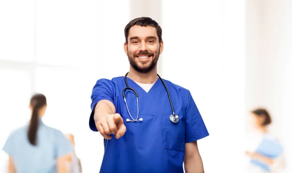 Médico sonriente o enfermero masculino apuntando a la cámara — Foto de Stock