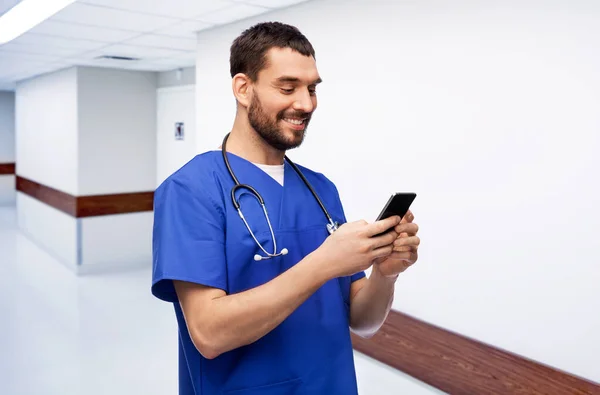 Médico sonriente o enfermero masculino usando teléfono inteligente —  Fotos de Stock