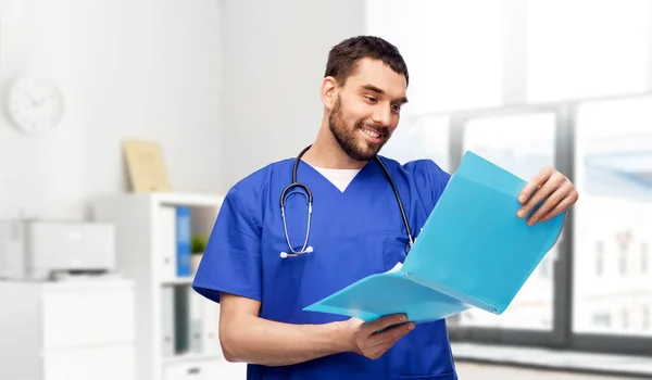 Glad manlig läkare läsa medicinsk rapport i mappen — Stockfoto