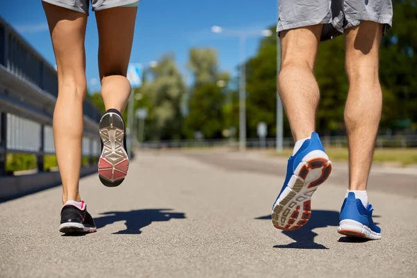 Nohy sportovního páru běží podél městské silnice — Stock fotografie