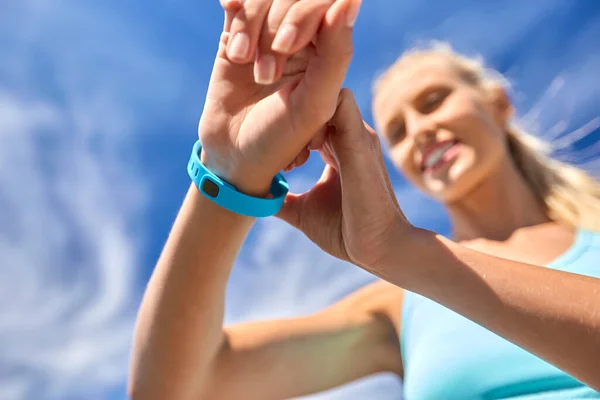 Leende ung kvinna med fitness tracker utomhus — Stockfoto