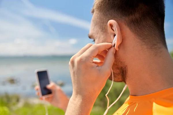 Young man with smartphone and earphones outdoors — Stock Photo, Image