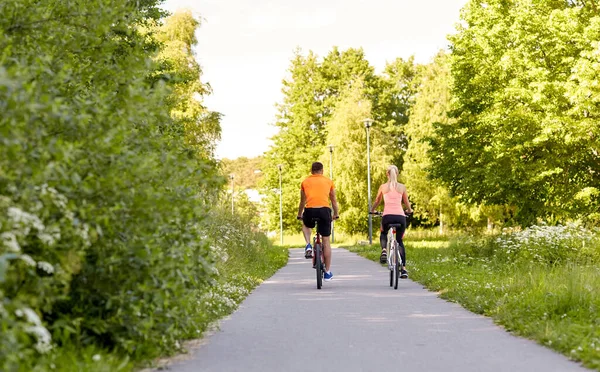 Young couple riding bicycles in summer park — Stock Photo, Image