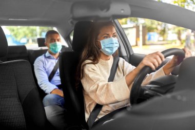 female driver in mask driving car with passenger clipart