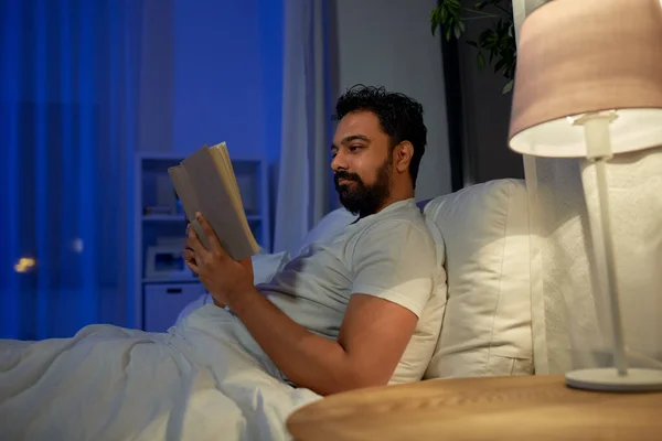 インド人男性が夜にベッドで本を読む — ストック写真