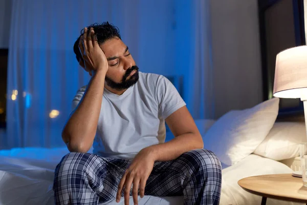 Стресований індійський чоловік сидить на ліжку вночі — стокове фото