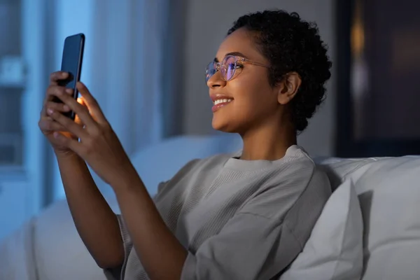Mulher africana com smartphone na cama à noite — Fotografia de Stock